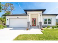 Charming single-story home with a well-manicured lawn, red front door, and two-car garage at 482 Sunset N Rd, Rotonda West, FL 33947