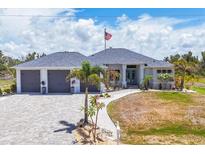 Beautiful home featuring a three car garage, paver driveway, and manicured landscaping at 530 Spaniards Rd, Placida, FL 33946