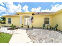 Charming single-story home featuring a welcoming front entrance with decorative columns and outdoor seating at 6158 Cavan St, Englewood, FL 34224