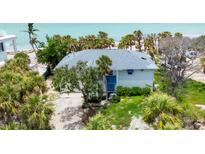 Coastal home featuring lush tropical landscaping, a gray roof, and a serene view of the beach and ocean at 7420 Manasota Key Rd, Englewood, FL 34223