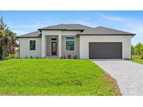 Beautiful one-story home featuring a well-manicured lawn and a modern two-car garage at 8105 Antwerp Cir, Port Charlotte, FL 33981