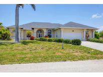 Lovely single-story home with manicured lawn, shrubbery and attached two-car garage at 1002 Rotonda Cir, Rotonda West, FL 33947