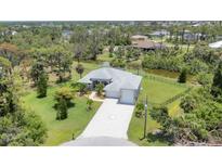 Stunning aerial view of a gray home with a water view, manicured lawn, and spacious driveway at 124 Cutlass Dr, Rotonda West, FL 33947