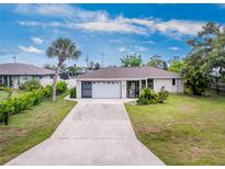 Charming single-story home featuring a two-car garage and a well-manicured front yard with mature trees at 1337 Le Pera Rd, Englewood, FL 34223