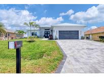 Beautiful single-story home with a lush green lawn, stone accents, and a gray paved driveway at 15610 Staunton Cir, Port Charlotte, FL 33981