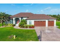 Charming single Gathering home showcasing a three-car garage, lush landscaping, and a well manicured green lawn at 204 W Pine Valley Ln, Rotonda West, FL 33947