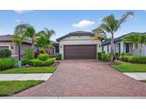 Charming single-story home with a brick driveway, manicured landscaping, and a two-car garage at 2592 Brassica Dr, North Port, FL 34289