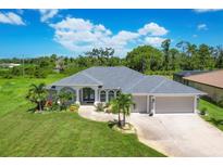 Charming single-story home featuring a well-manicured lawn, mature trees and a two-car garage at 423 Boundary Blvd, Rotonda West, FL 33947