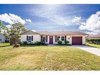 Charming single-story home featuring a well-manicured lawn, attached garage, and delightful curb appeal at 4399 Mundella Cir, Port Charlotte, FL 33948