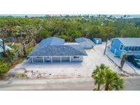 Charming single-story home with a large yard, lush landscaping, and a detached garage at 608 Saint Judes Dr, Longboat Key, FL 34228