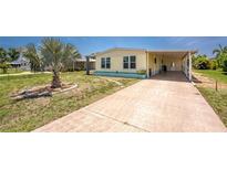 Charming yellow home featuring a well-manicured yard, large driveway, and a convenient covered parking area at 6293 Sparrow Ln, Englewood, FL 34224