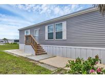 Charming home with a tidy gray exterior and wooden steps to the front door at 7337 Desant Ln, Port Charlotte, FL 33981