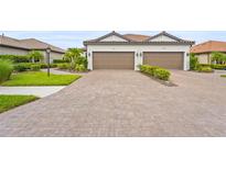 Charming villa with a two-car garage, brick driveway and tile roof, complemented by neat landscaping at 10258 Morning Mist Ln, Sarasota, FL 34241