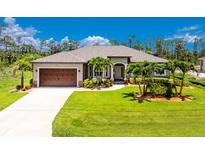 Beautiful single-story home featuring a manicured lawn and a large, attached two-car garage at 1119 Boundary Blvd, Rotonda West, FL 33947