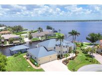 Expansive waterfront home boasts lush landscaping, a private boat dock, and stunning river views at 12438 Prather Ave, Port Charlotte, FL 33981