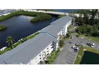 Scenic aerial view of a waterfront condo building with lush landscaping and parking area at 1401 S Mccall Rd # 101, Englewood, FL 34223