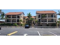 Condominium complex with a two-story building, parking, and surrounding palm trees at 1760 Gulf Blvd # 511, Englewood, FL 34223