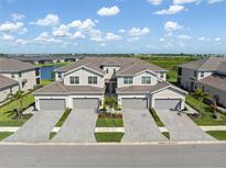 Aerial view of multi-Gathering homes with garages and manicured landscaping near a scenic lake and lush green spaces at 17605 Boracay Ct # 201, Venice, FL 34293