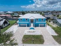 Stunning elevated home features a two-car garage, light blue paint, white trim, and a paved driveway and walkway at 1930 Massachusetts Ave, Englewood, FL 34224