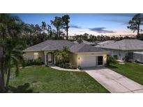 Charming single-story home with a well-manicured lawn, mature trees, and a two-car garage at 2588 Westberry Ter, North Port, FL 34286