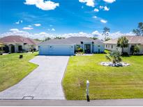 Beautiful light blue single-story home with a well-manicured lawn and a long driveway leading to an attached two-car garage at 262 Rotonda N Blvd, Rotonda West, FL 33947