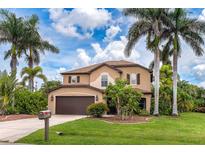 Beautiful two-story home featuring a manicured lawn, two car garage and lush tropical landscaping at 26294 Bridgewater Rd, Punta Gorda, FL 33983