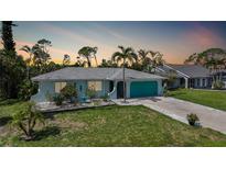 Charming single-story home with a well-manicured lawn, tropical landscaping and turquoise accents at 55 Mark Twain Ln, Rotonda West, FL 33947