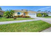 Charming home featuring a well-manicured lawn, lush landscaping, and a welcoming two-car garage at 576 Box Elder Ct, Englewood, FL 34223
