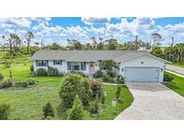 Charming single-story home featuring a manicured lawn and an inviting pink front door at 7690 Castleberry Ter, Englewood, FL 34224