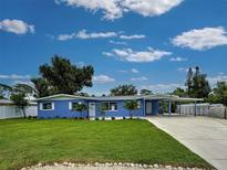 Charming blue single-story home with a well-manicured lawn and covered carport at 1295 S Maryknoll Rd, Englewood, FL 34223