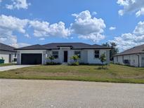 Charming one-story home with well-manicured front lawn and attached two car garage, plus some decorative palms at 14149 Whittier Ln, Port Charlotte, FL 33981