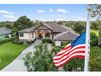 Elegant home exterior showcasing manicured lawn, mature trees, and a charming entrance at 1415 Bayshore Dr, Englewood, FL 34223