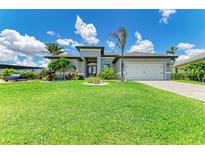 Beautiful single-story home with a manicured lawn, tropical landscaping, and a two-car garage at 15498 Seafoam Cir, Port Charlotte, FL 33981