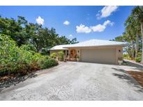 Charming single-story home with a metal roof, lush landscaping, and a wide driveway at 1733 Belvidere Rd, Englewood, FL 34223