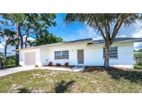 Charming single-story home featuring a well-maintained lawn and mature trees at 1785 Morning Dove Ln, Englewood, FL 34224
