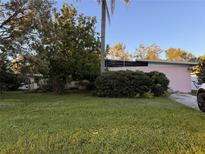 A charming single-story home with an expansive green lawn and mature trees in a quiet neighborhood setting at 2911 Novus St, Sarasota, FL 34237