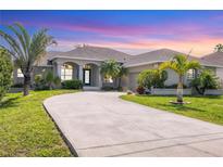 Charming home featuring a well-manicured lawn, circular driveway and tropical landscaping at 39 Pine Valley Ct, Rotonda West, FL 33947