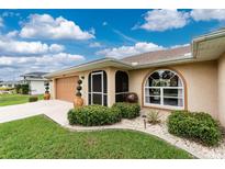 Charming home with a well-manicured lawn, a decorative landscape, and a tan-colored exterior at 4227 Winona St, Port Charlotte, FL 33948