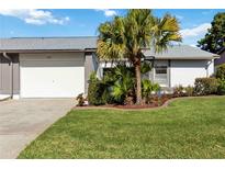 Charming home featuring a well-manicured lawn, mature palm tree, and an attached single-car garage at 609 Deerwood Ave, Englewood, FL 34223