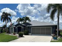 Charming single-story home with a well-manicured lawn, mature palm trees, and a two-car garage at 7130 Scarlet Sage Ct, Punta Gorda, FL 33955
