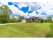 A charming single-story home featuring a manicured lawn, attached garage and a covered entrance, nestled under a sunny sky at 7376 Stetson Ln, Port Charlotte, FL 33981