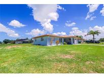 Well-maintained single-story home with a large, green lawn and light blue exterior under a clear blue sky at 7437 Bass St, Englewood, FL 34224