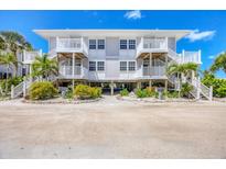 Two-story beach home with white railings, stairs, and lush tropical landscaping adding coastal charm at 7486 Palm Island Dr # 2413, Boca Grande, FL 33921