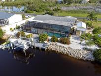 Aerial view of a home featuring a screened pool, dock, and canal access at 1030 Haste Ln, Englewood, FL 34223
