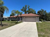 Charming single-story home with a large two-car garage and a well-manicured lawn at 18122 Windswept Ave, Port Charlotte, FL 33948