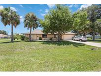 Charming single-story home with a well-manicured lawn, mature trees, and welcoming curb appeal at 27581 Tierra Del Fuego Cir, Punta Gorda, FL 33983