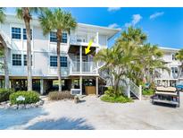 Inviting elevated coastal condo showcasing a pristine white exterior and lush tropical landscaping at 7500 Palm Island S Dr # 2111, Placida, FL 33946