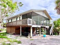 Charming coastal home featuring a screened porch and spacious outdoor living area on a stilt foundation at 8416 Little Gasparilla Is, Placida, FL 33946