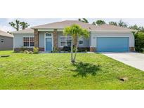 Charming single-story home featuring a well-manicured lawn, stone accents, and a bright blue garage door at 9151 Melody Cir, Port Charlotte, FL 33981