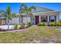 Charming home featuring a two-car garage, red shutters, a red front door and lush landscaping at 9213 Spring Cir, Port Charlotte, FL 33981